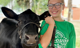 A young girl with her cow on a lead