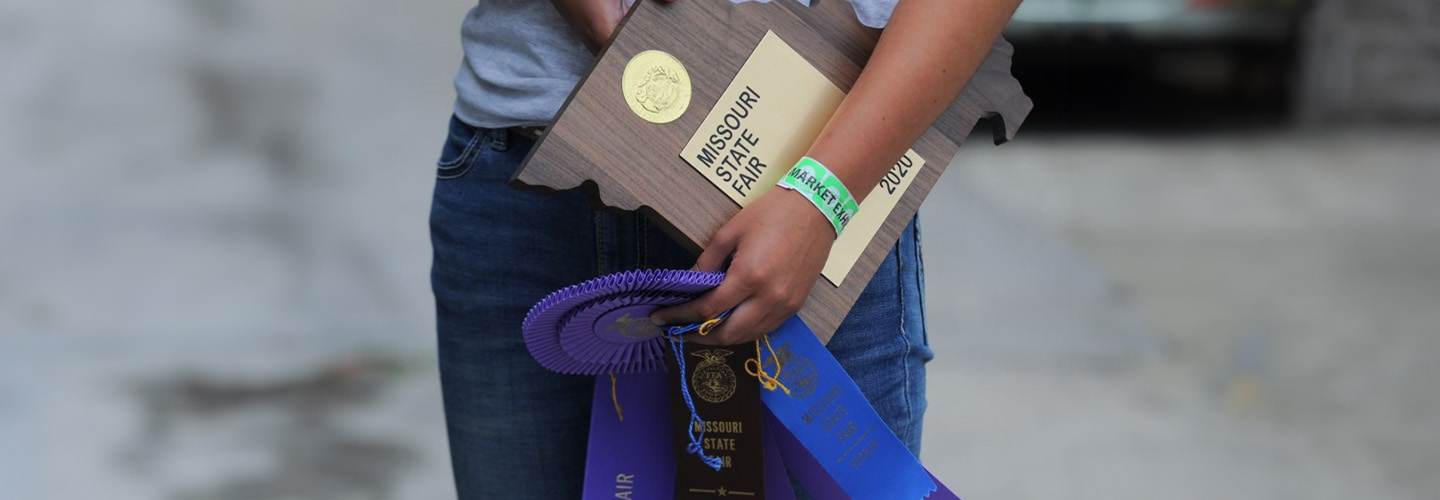 Youth fair competitor holding a ribbon and award plaque