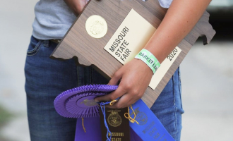 Youth fair competitor holding a ribbon and award plaque