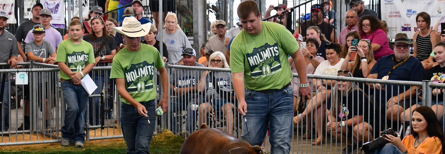A exhibitor and ambassador showing a pig while a crowd watches